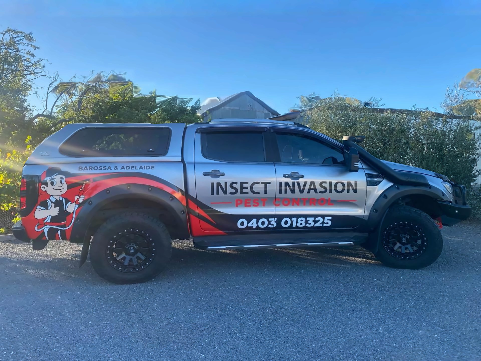 The Insect Invasion Pest Control Ford Ranger ute — silver, red and black wrap with the door branding, 0403 018 325 and the mascot, servicing the Barossa & Adelaide